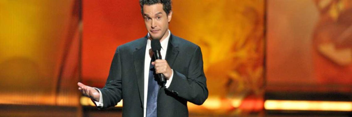 eric performing comedy on a stage at the emmy awards