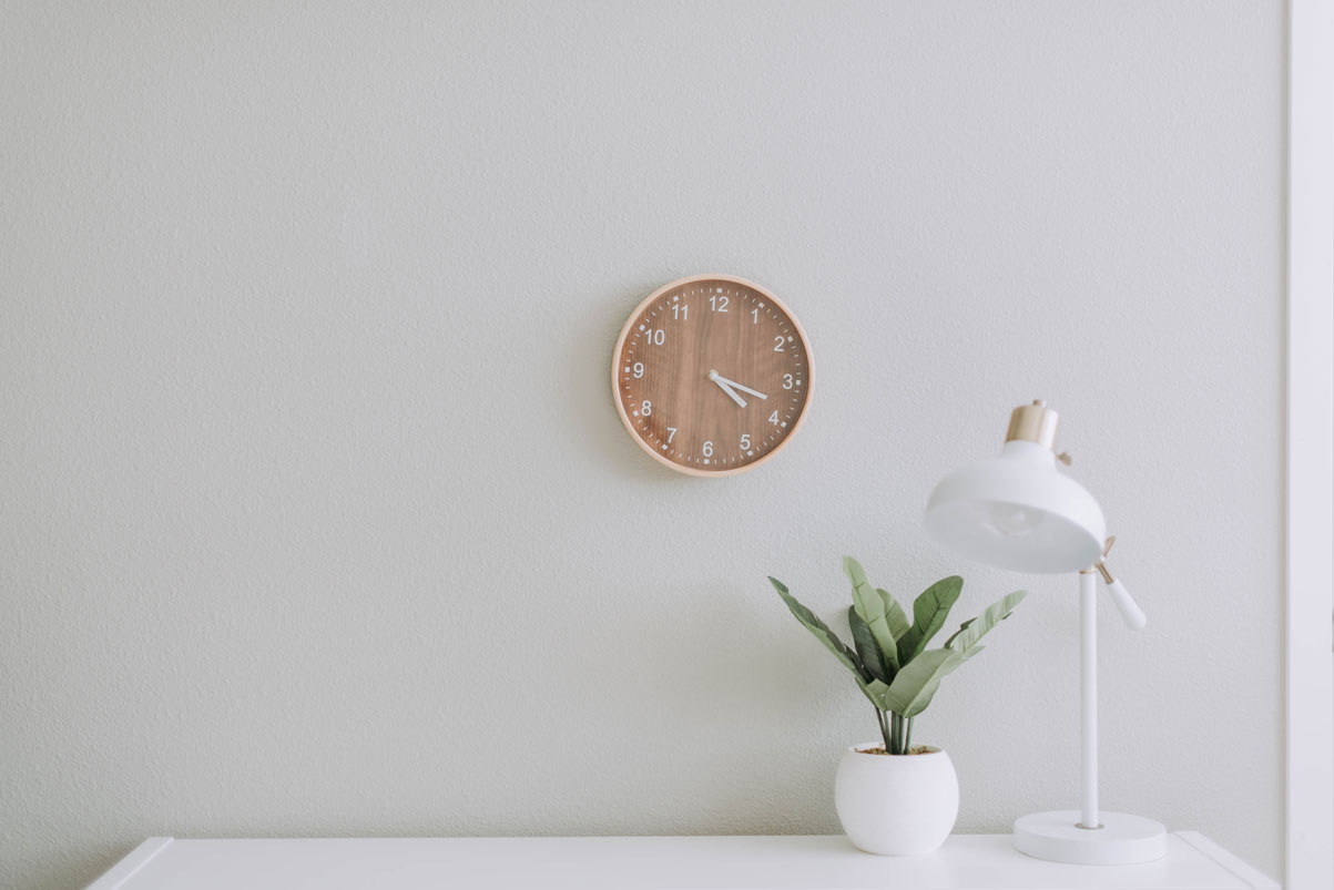 a table with a plant and a clock on the wall