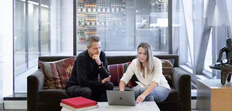 two people on a couch looking at a computer and negotiating