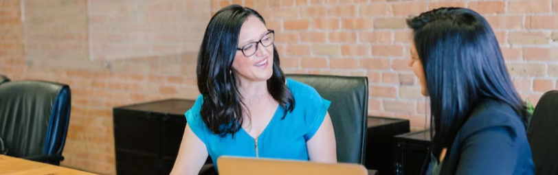 two people sitting at a computer talking