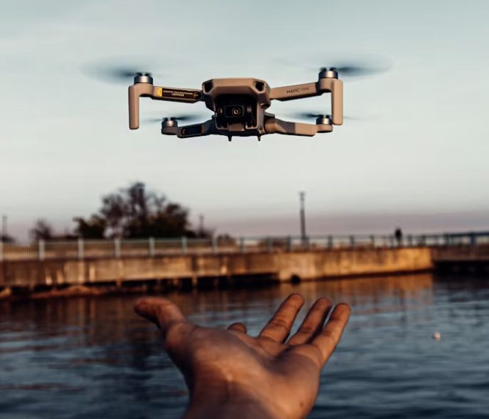 a drone flying over a lake with a hand launching it