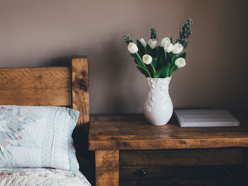 a bedside table with a pot of flowers on it